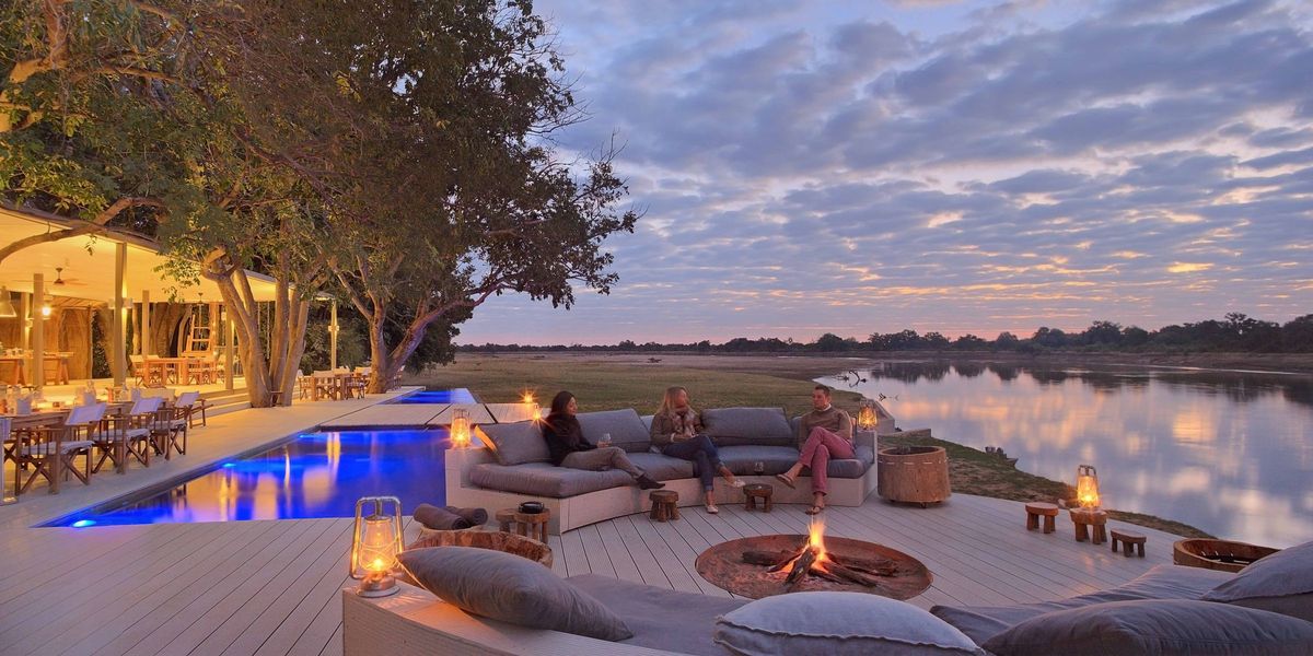 Sit around a campfire on the main deck overlooking the river's wildlife at Chinzombo, South Luangwa National Park, Zambia